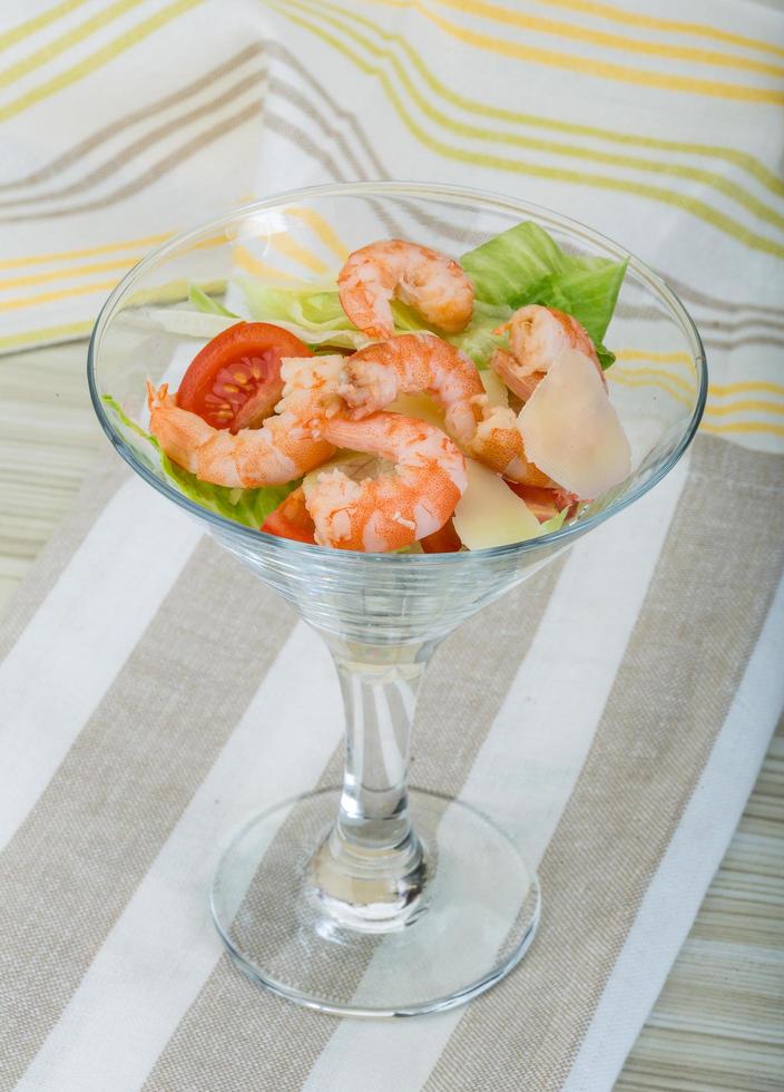 Caesar salad with shrimps on wooden background photo