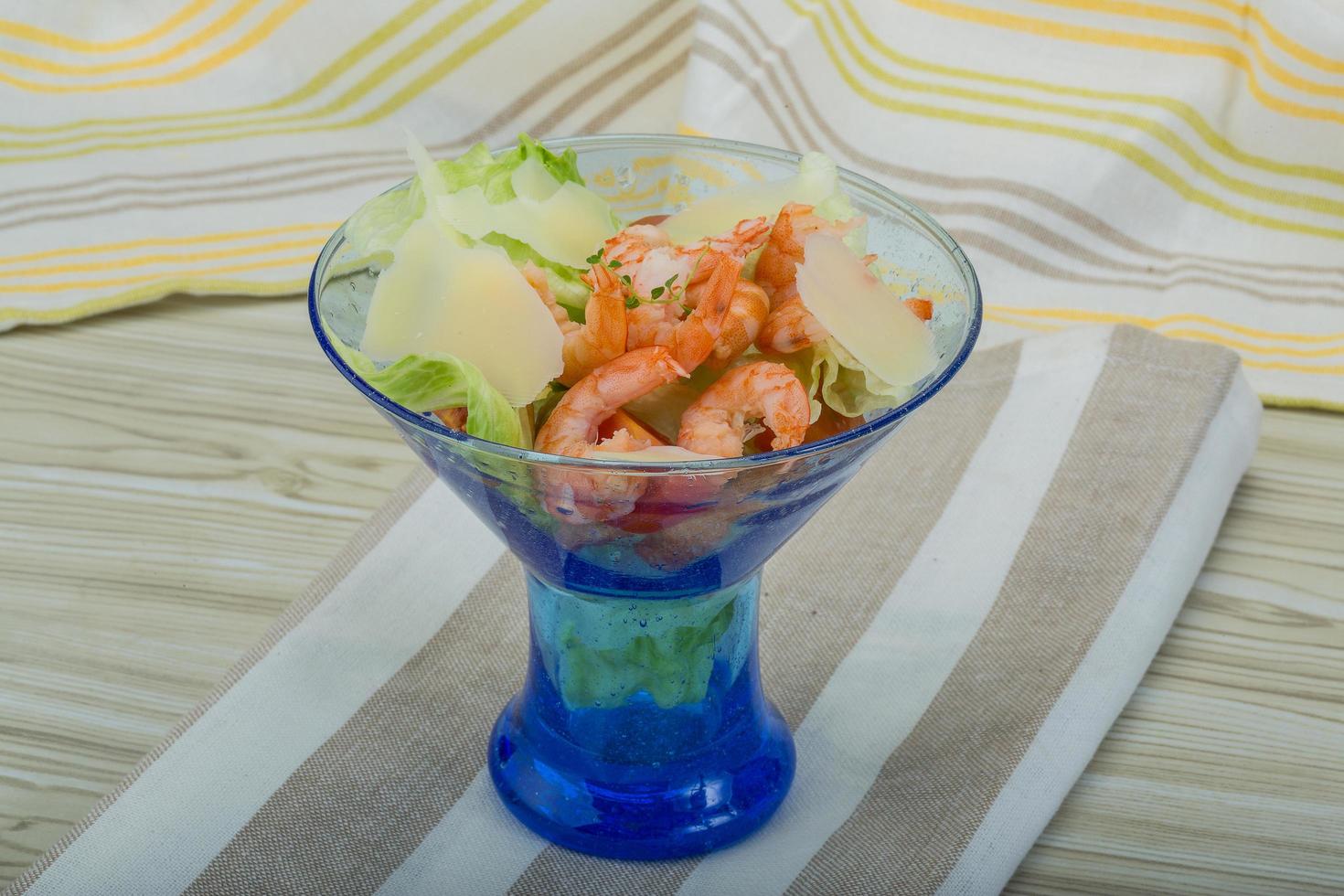 Caesar salad with shrimps in a bowl on wooden background photo