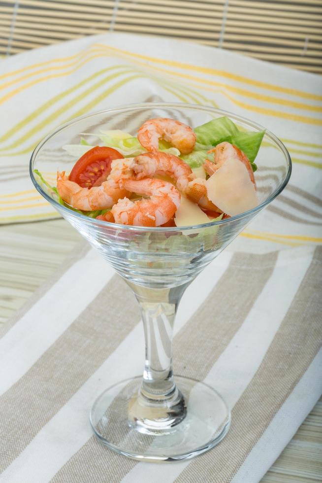 Caesar salad with shrimps on wooden background photo