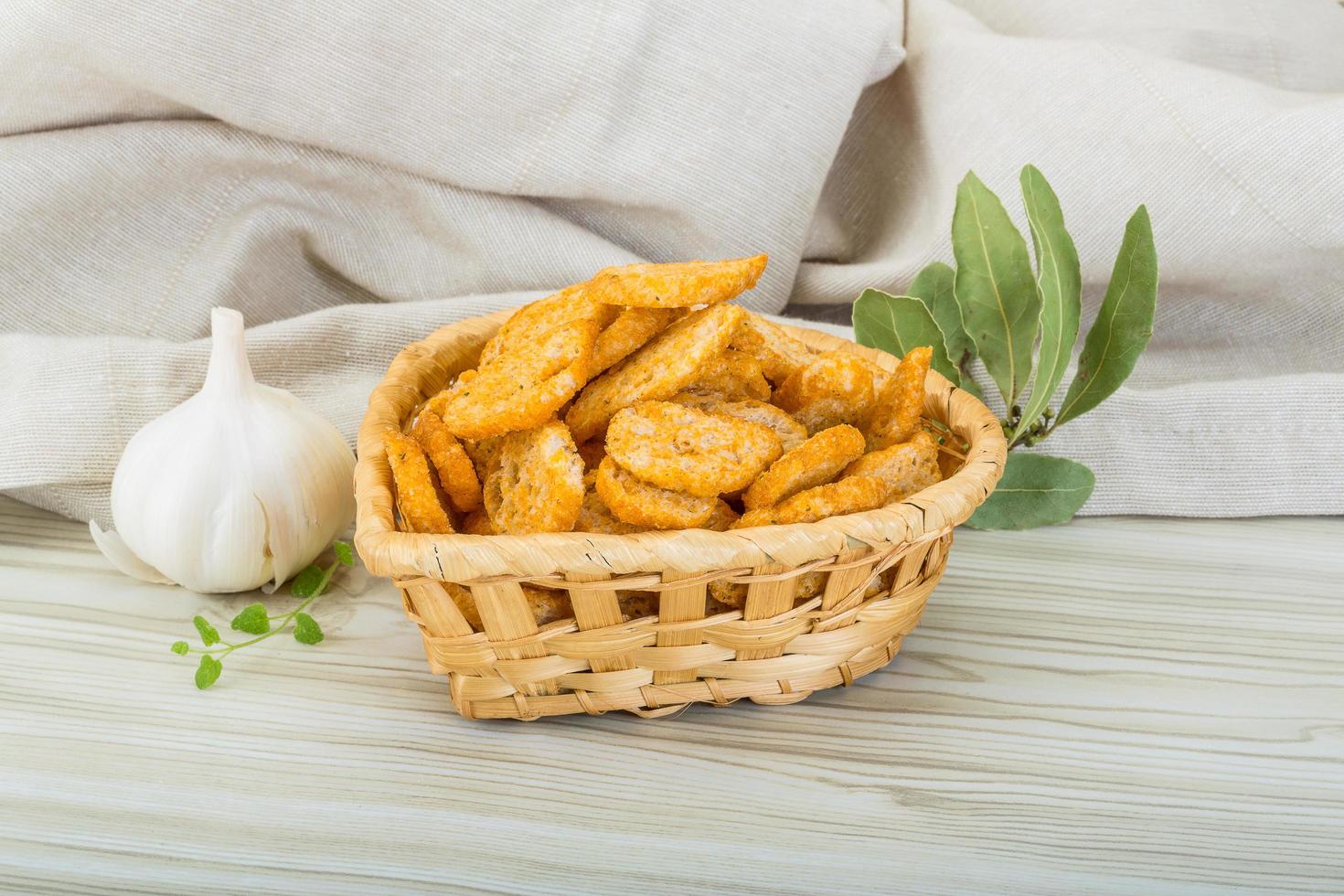 Croutons in a basket on wooden background photo