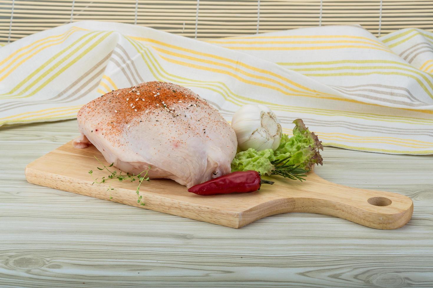 Raw chicken breast on wooden board and wooden background photo