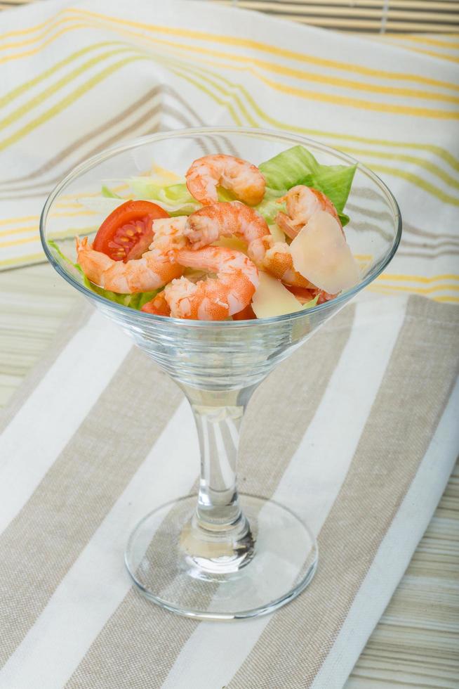 Caesar salad with shrimps on wooden background photo