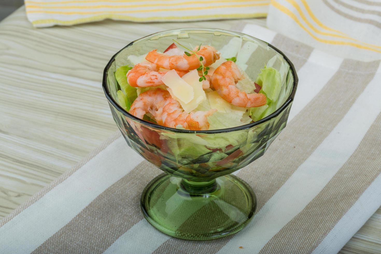 Caesar salad with shrimps in a bowl on wooden background photo