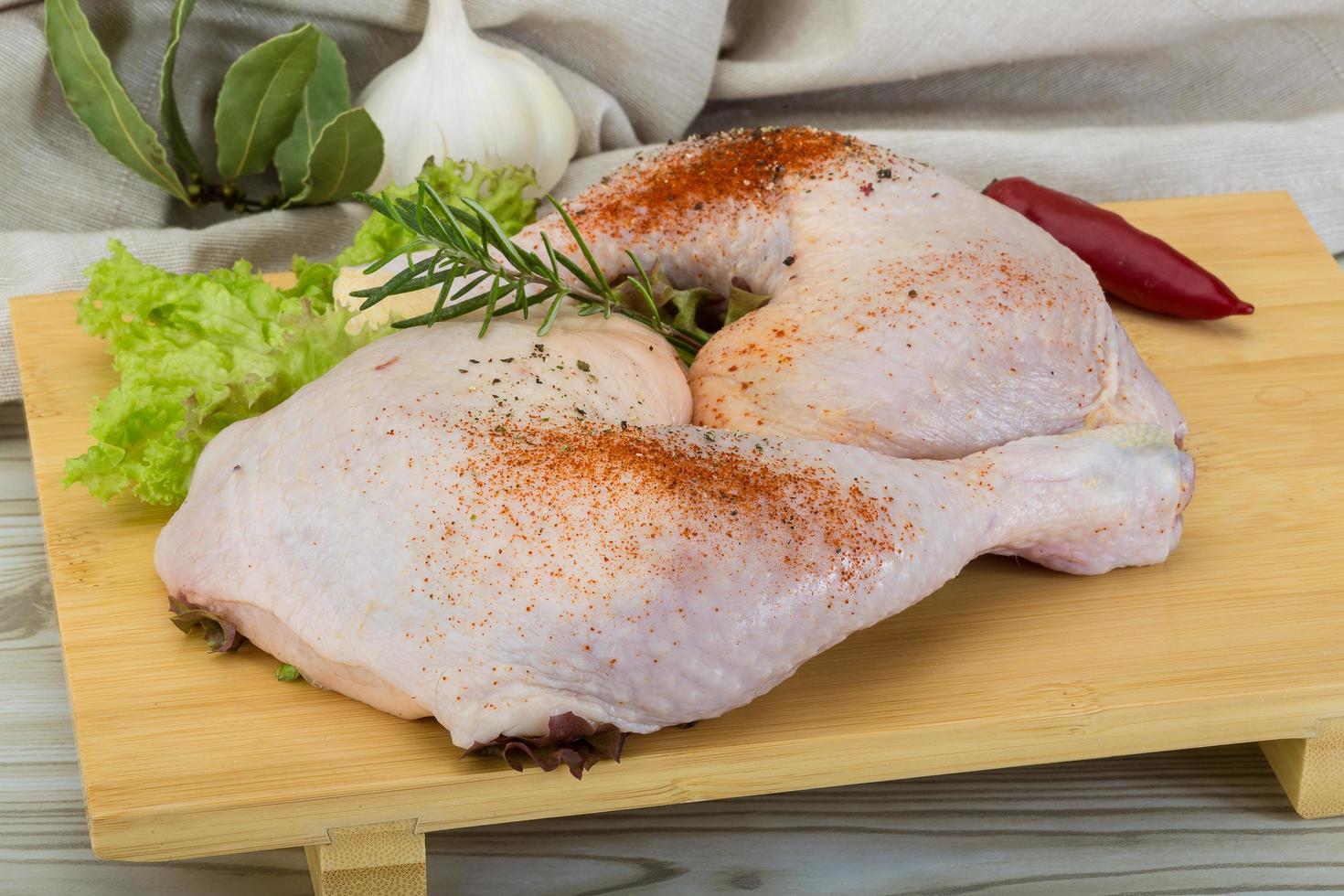 Chicken thigh on wooden board and wooden background photo