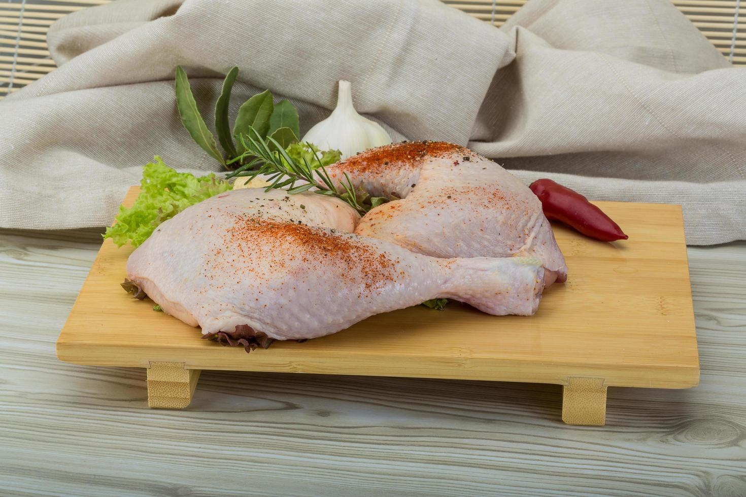 Chicken thigh on wooden board and wooden background photo