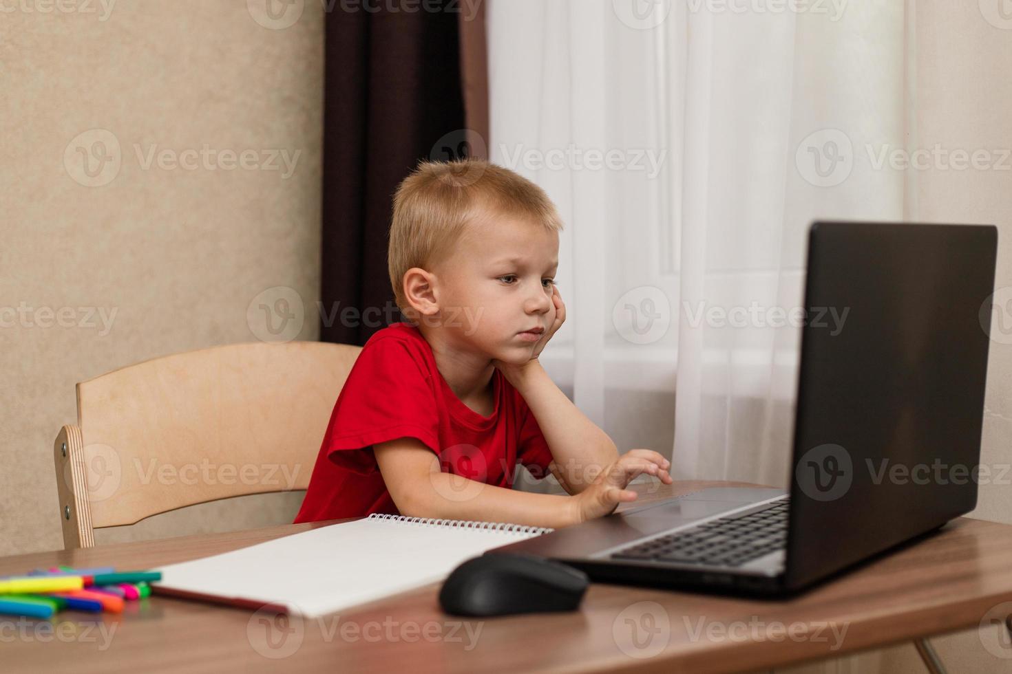 Online distance learning. The child looks carefully at the laptop and studies the drawing lesson online on the Internet. Online school. photo