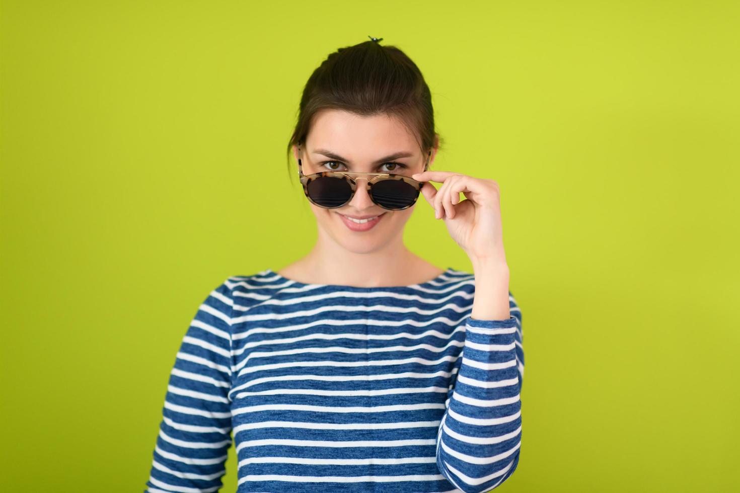 woman  in sunglasses posing in front of a green background photo