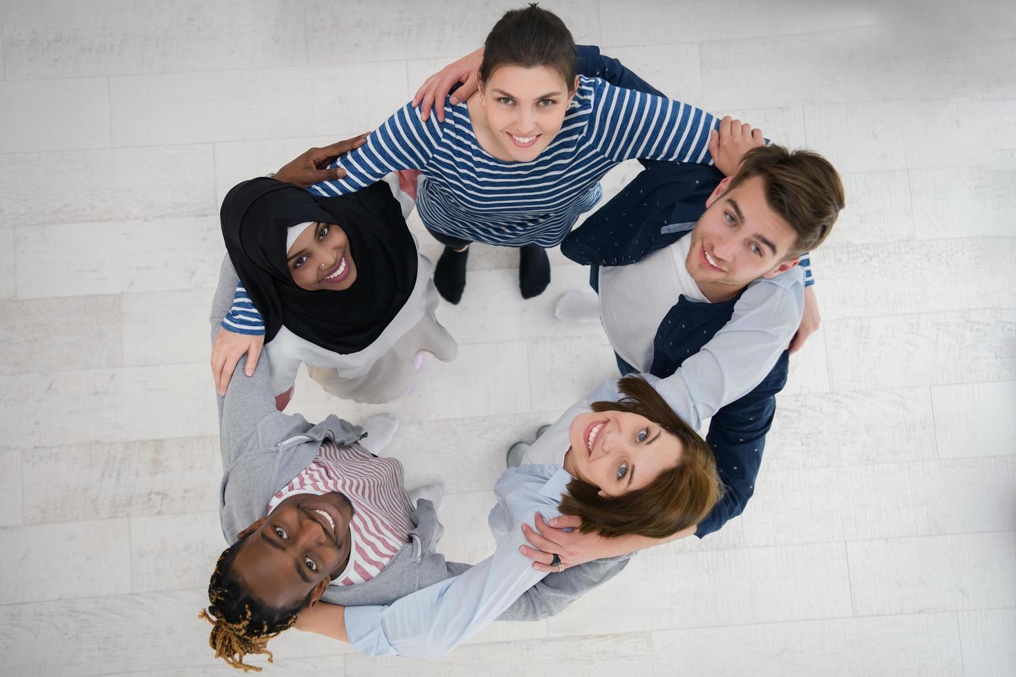 vista superior de un grupo diverso de personas de pie abrazando y simbolizando la unión foto