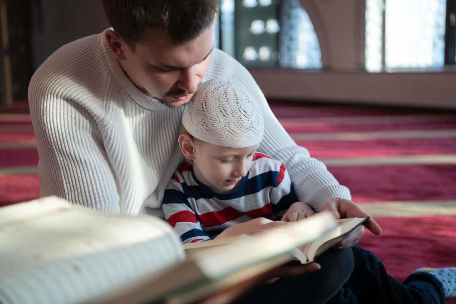 oración musulmana padre e hijo en la mezquita rezando y leyendo el libro de acebo corán juntos concepto de educación islámica foto
