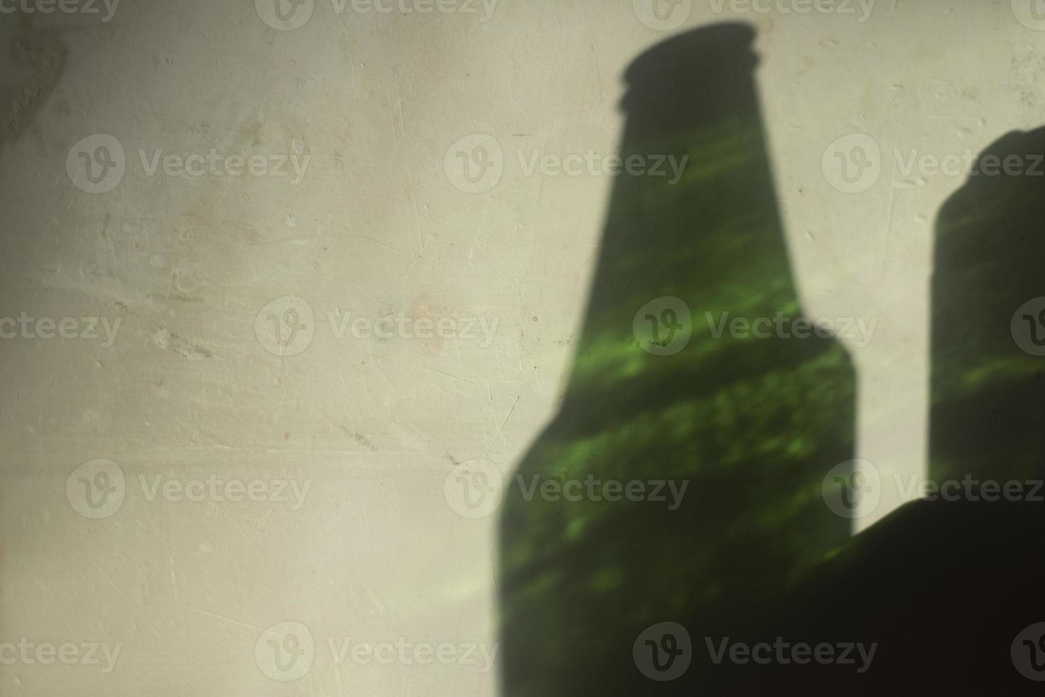 Light on wall from bottle of beer. Green glass and shadow on wall. photo