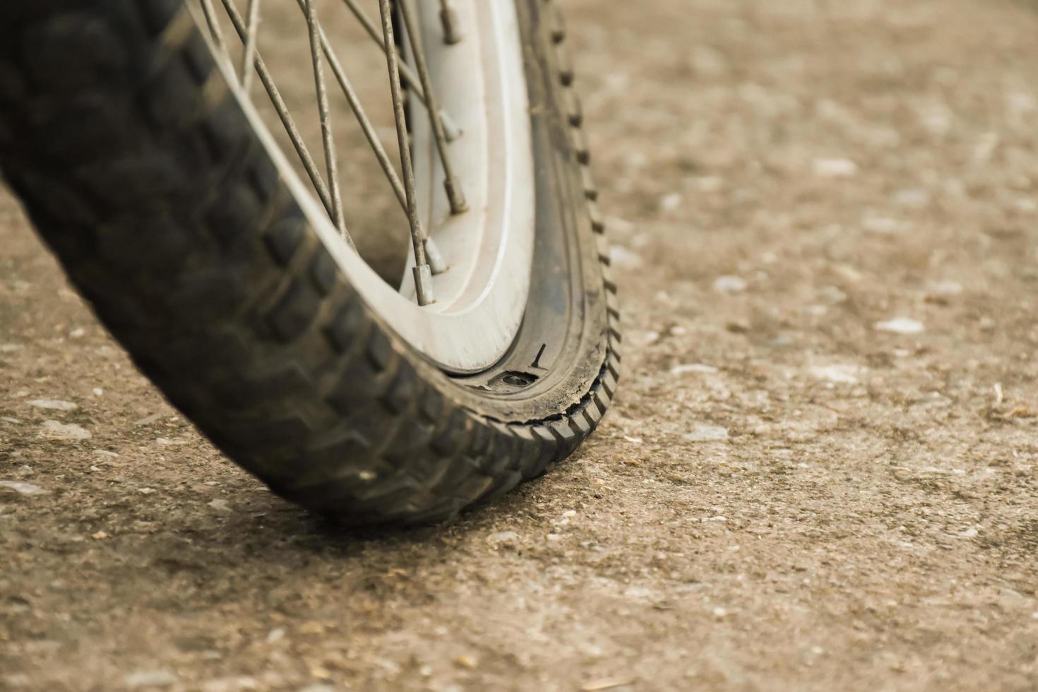 Close up view of bike which has flat tire and parked on the pavement, blurred background. Soft and selective focus on tire. photo