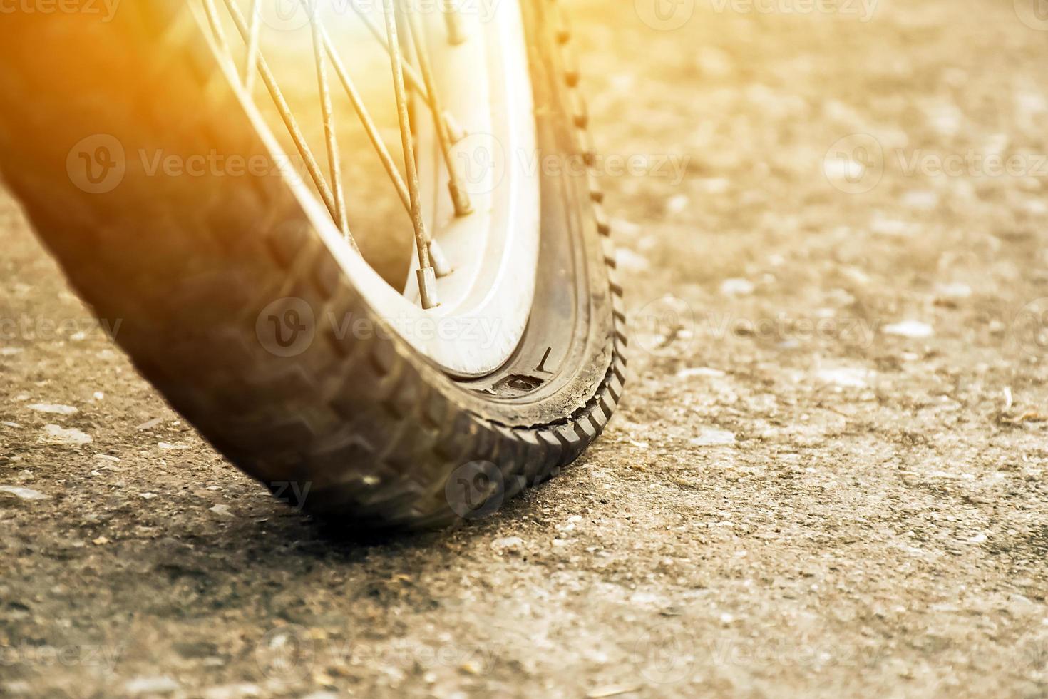 Close up view of bike which has flat tire and parked on the pavement, blurred background. Soft and selective focus on tire. photo