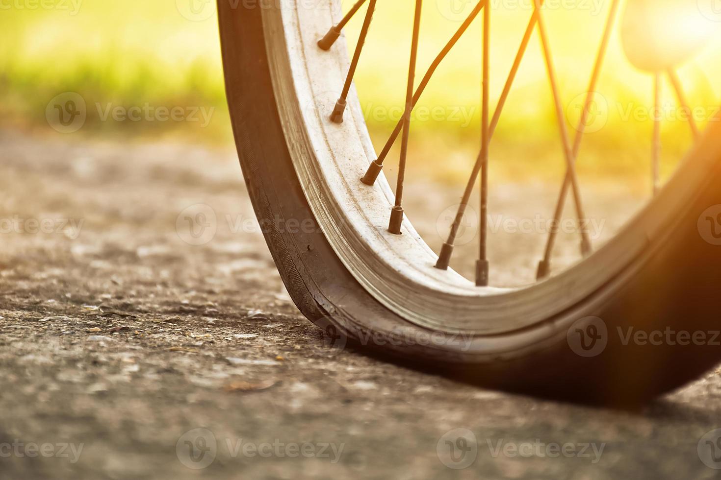 vista de cerca de la bicicleta que tiene un neumático desinflado y estacionado en el pavimento, fondo borroso. enfoque suave y selectivo en el neumático. foto