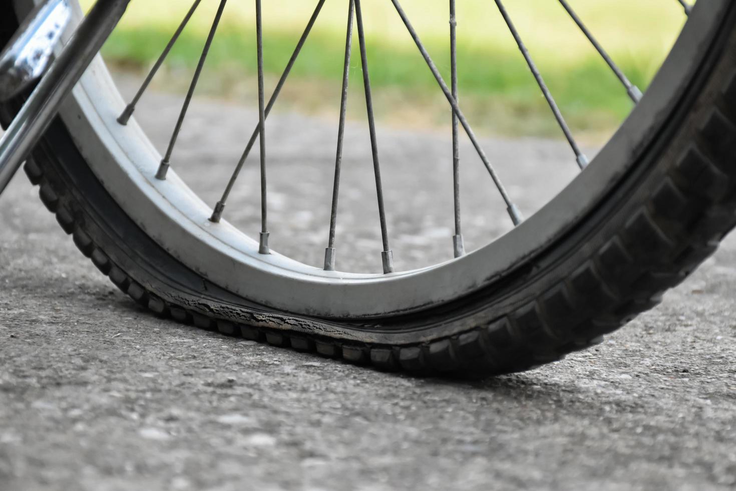 vista de cerca de la bicicleta que tiene un neumático desinflado y estacionado en el pavimento, fondo borroso. enfoque suave y selectivo en el neumático. foto