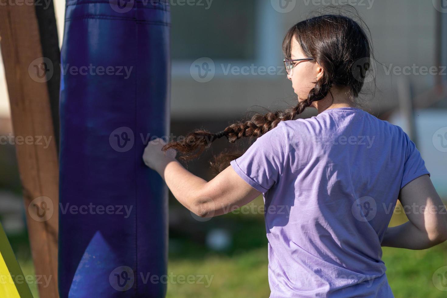 Girl punching sandbag. Muaythai boxing training. Healthy girl punching at boxing bag. Concept of boxing training, exercising, working out at fitness, sport photo