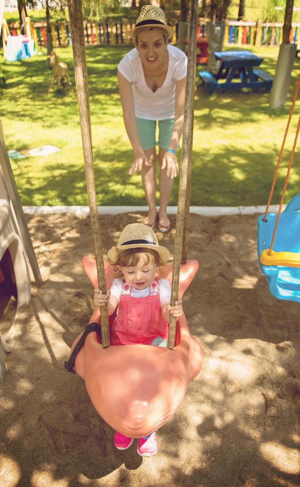 mother and daughter swinging in the park photo