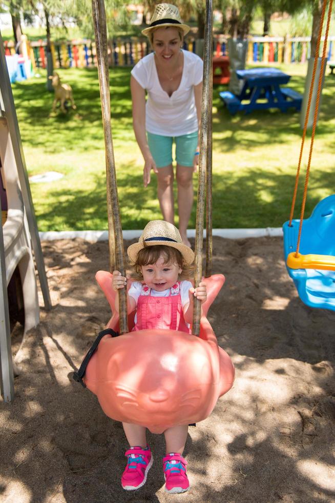 mother and daughter swinging in the park photo