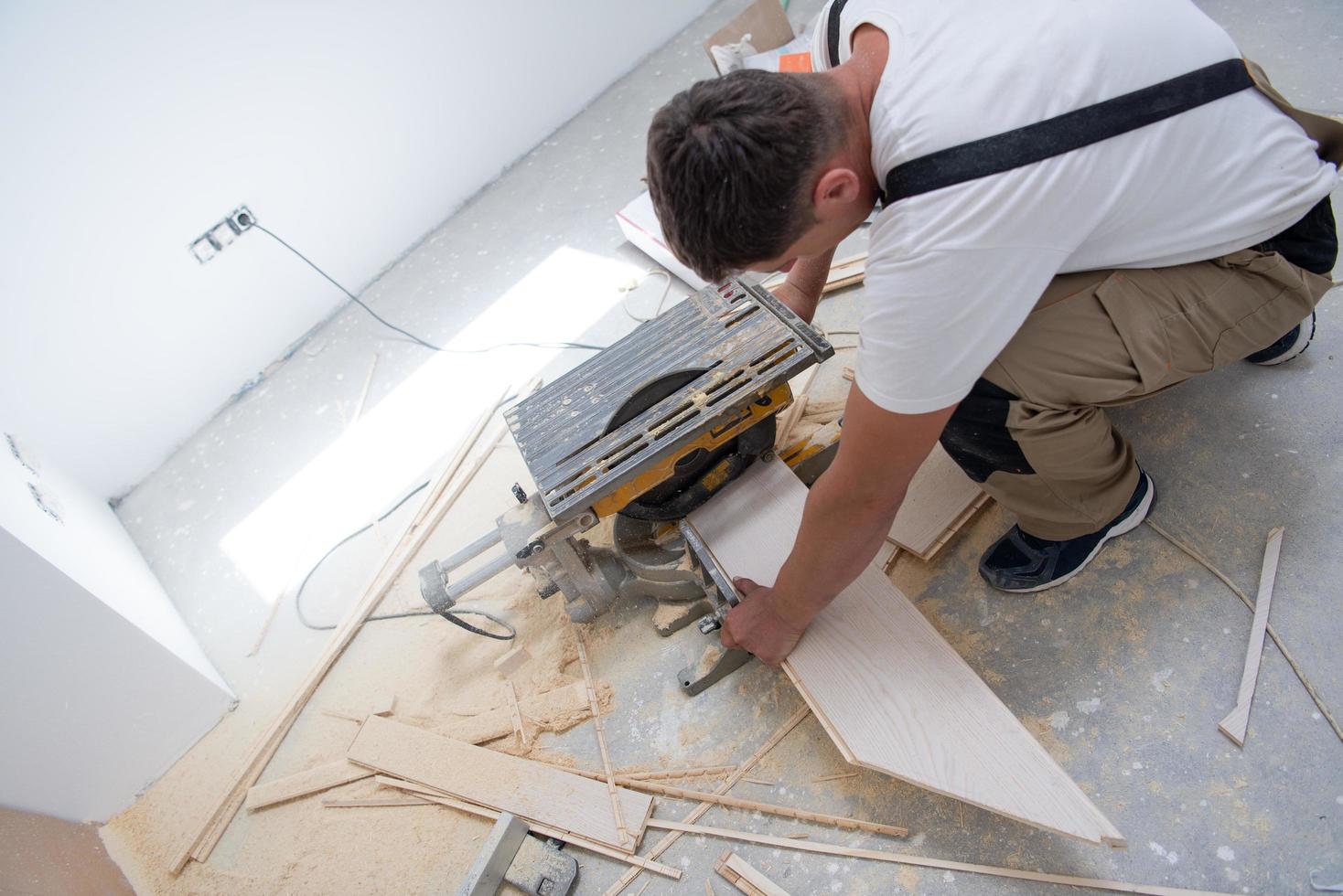 Man cutting laminate floor plank with electrical circular saw 11947736