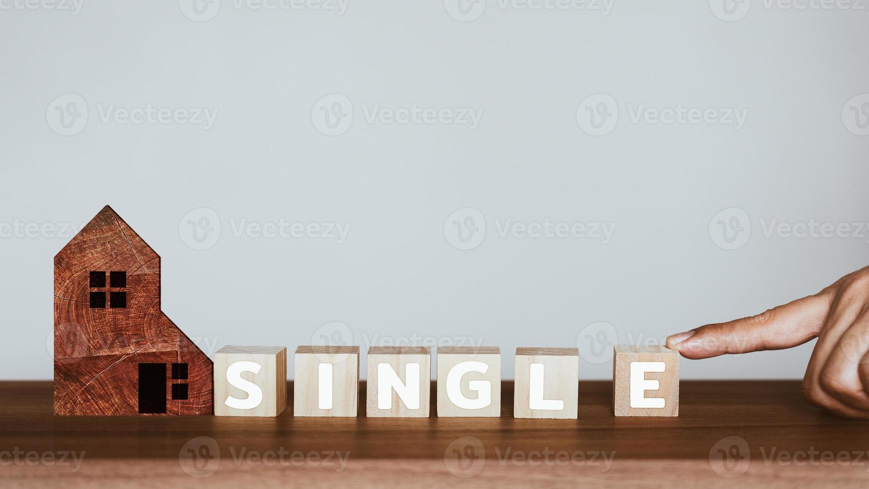 Man's hand scrolling the letter e to combine with the rest of the words to get the word single on wooden cubes block. photo