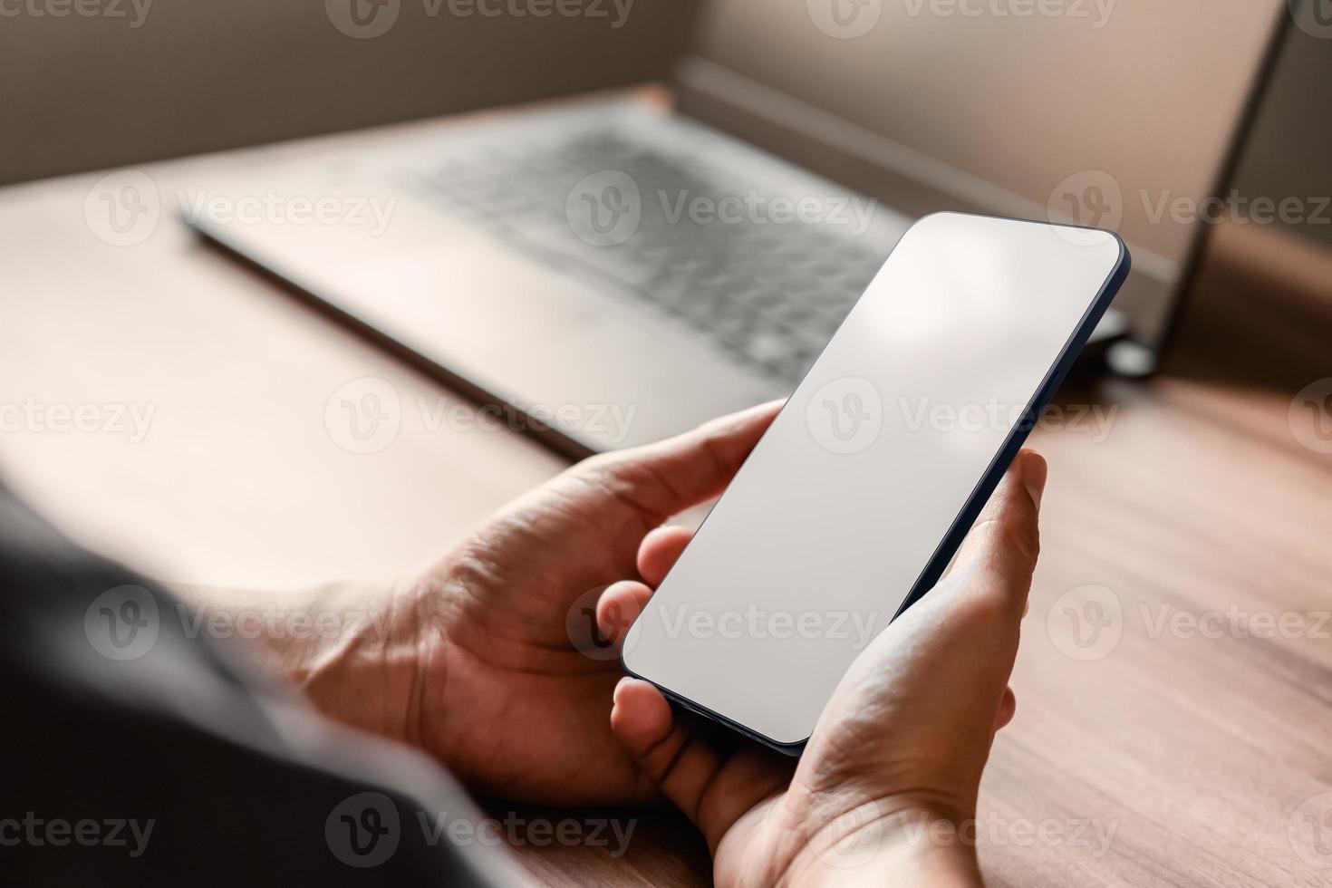 Mockup image of a man holding and using smartphone with blank desktop screen while working and drinking coffee in cafe. photo