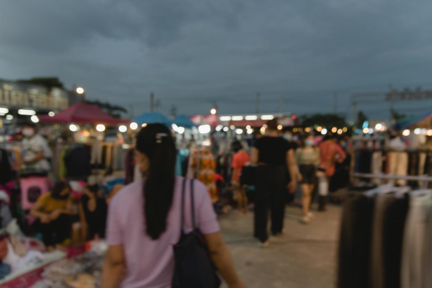 imagen borrosa de la gente del festival del mercado nocturno caminando por la carretera con un ligero bokeh de fondo. foto