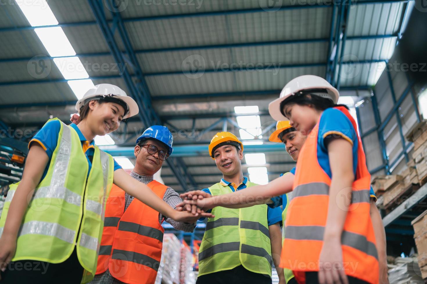 Group of industrial warehouse asian worker in safety suite hand stack celebrate successful or deal commitment. Logistics , supply chain and warehouse business.Teamwork unity under view concept. photo