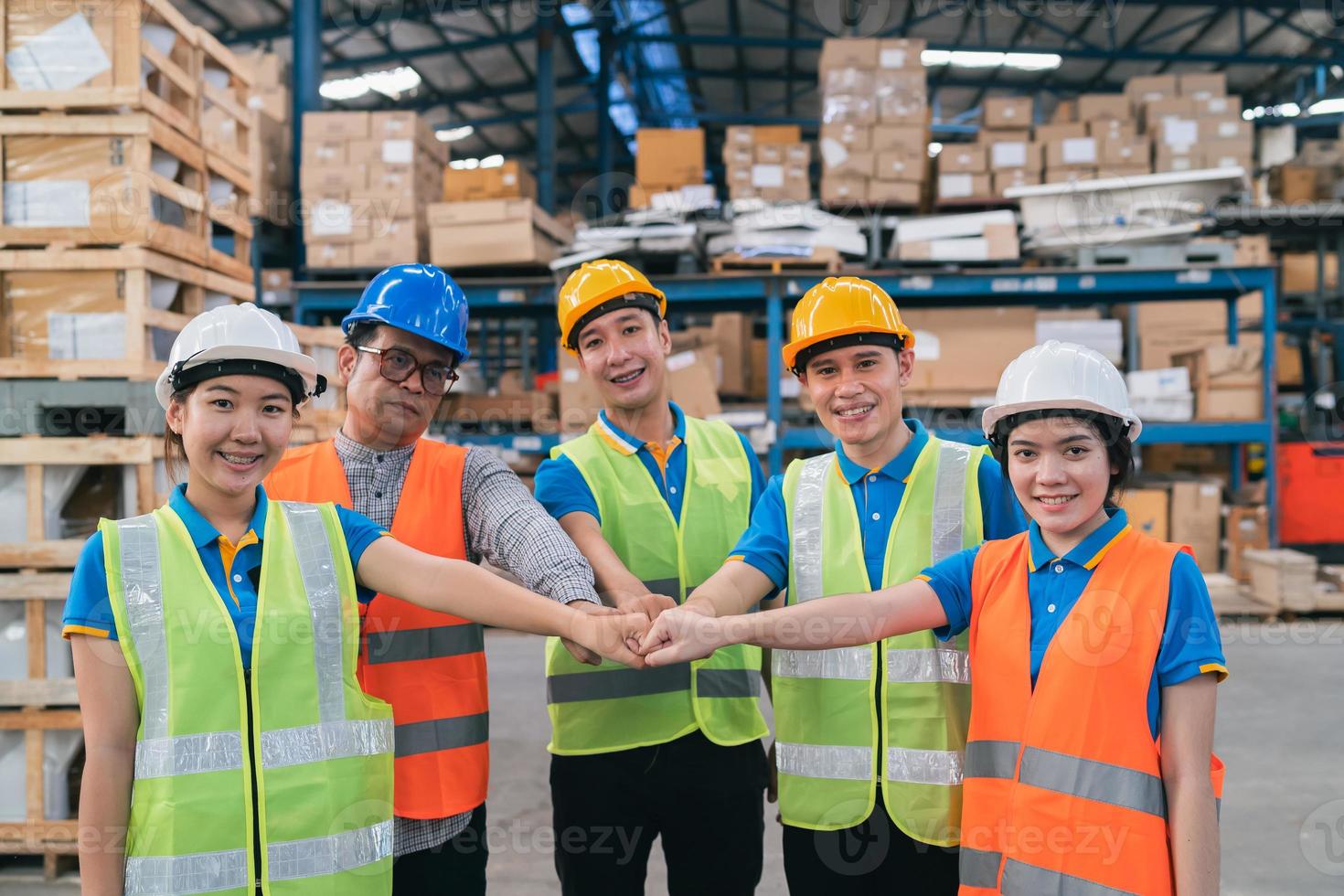 grupo de trabajadores asiáticos de almacenes industriales en la pila de mano de la suite de seguridad celebran el compromiso exitoso o de trato. Logística, cadena de suministro y negocio de almacén. Unidad de trabajo en equipo bajo el concepto de vista. foto