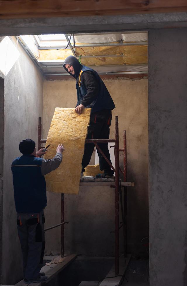 roofer man installing thermal insulation layer photo