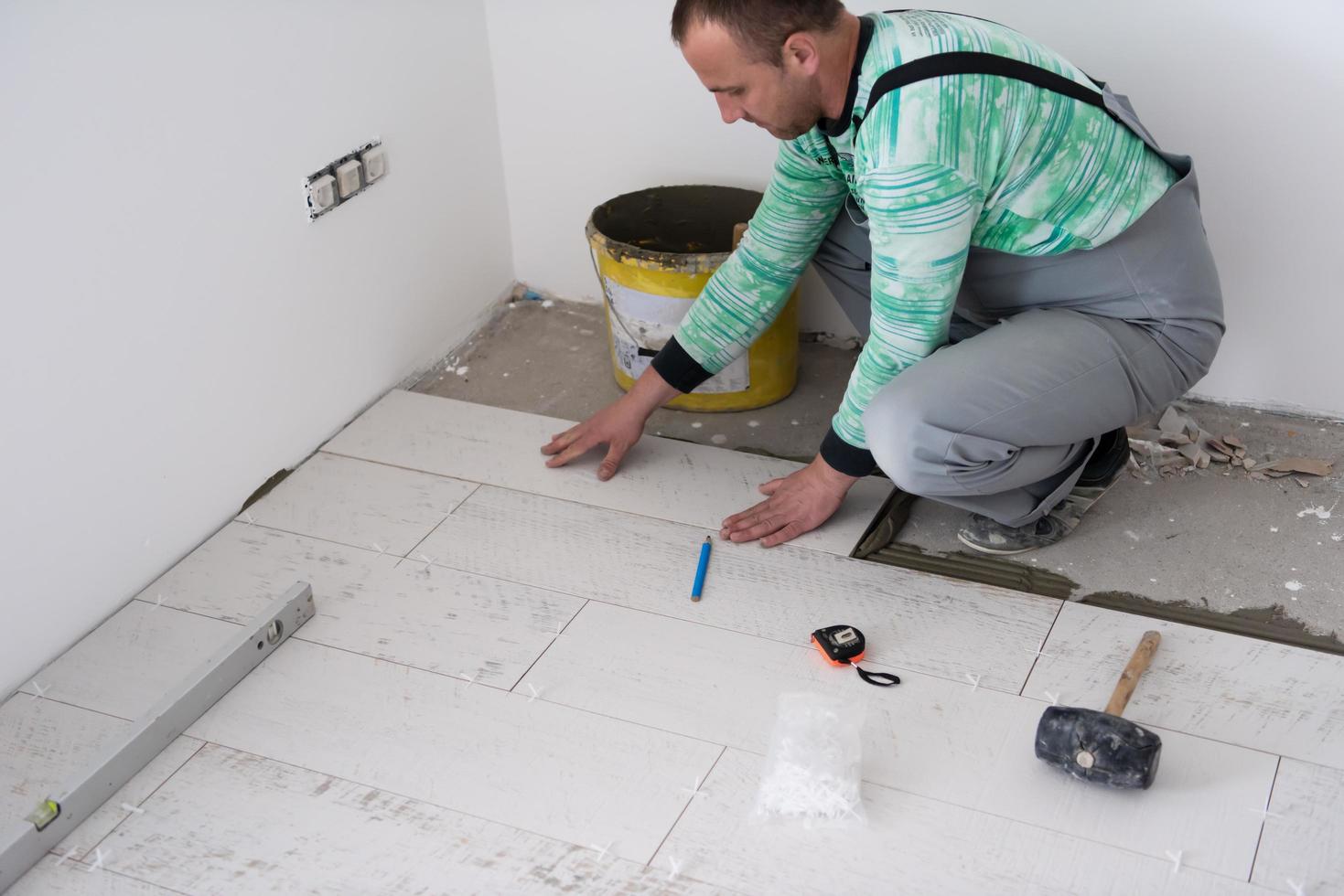 worker installing the ceramic wood effect tiles on the floor photo