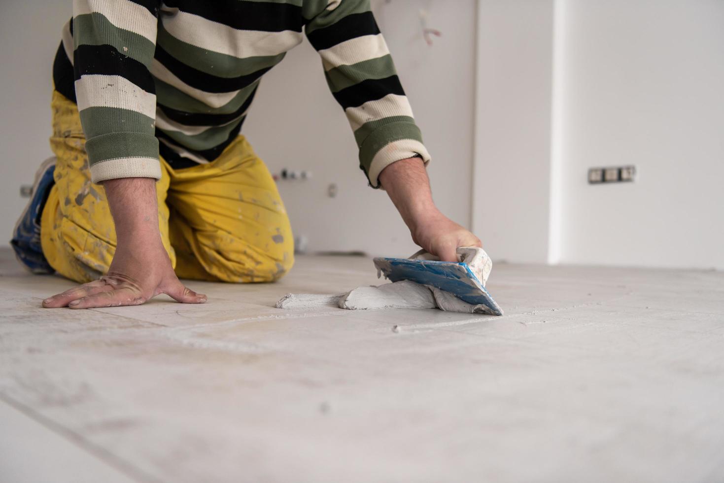 Tilers filling the space between ceramic wood effect tiles photo