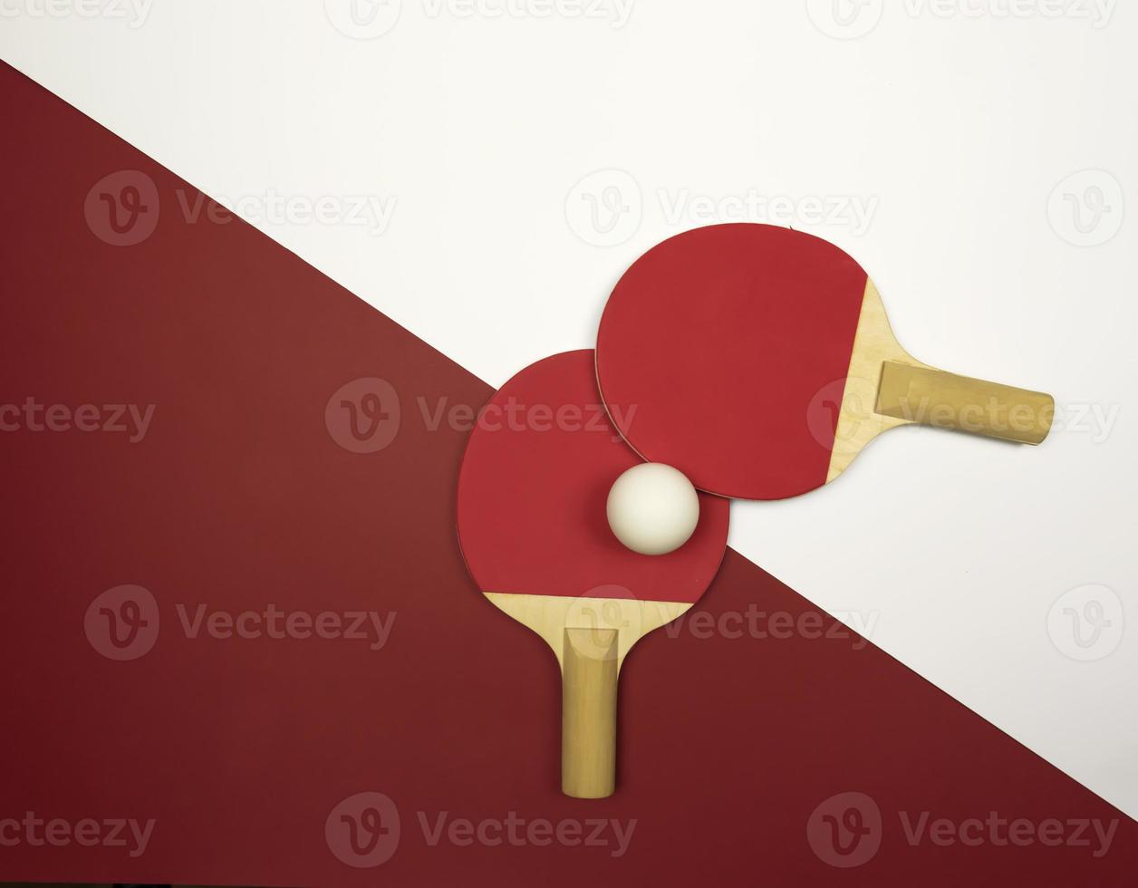 Two red table tennis rackets lying on a colorful background photo