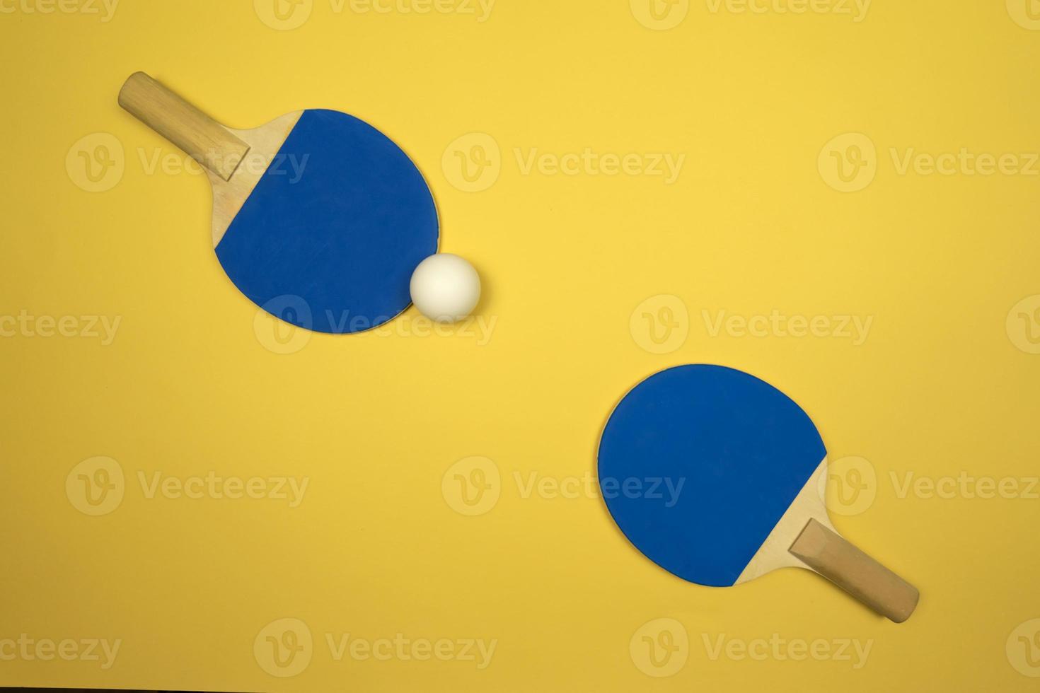 Two blue table tennis rackets lying on a yellow background 11953837
