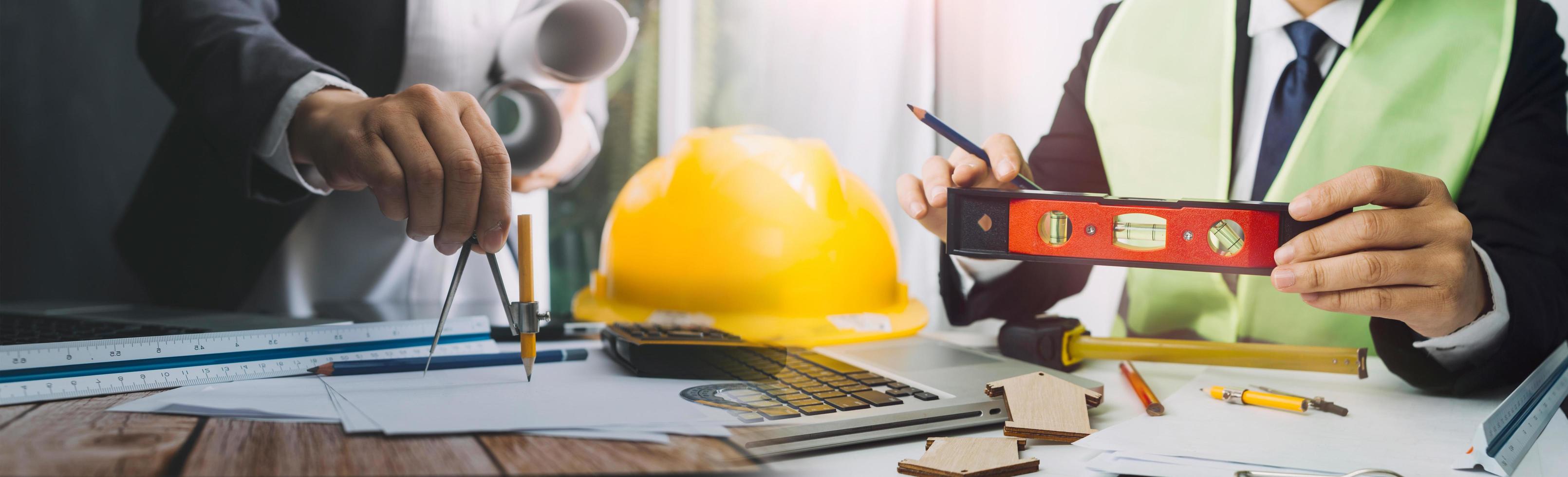 Two colleagues discussing data working and tablet, laptop with on on architectural project at construction site at desk in office photo