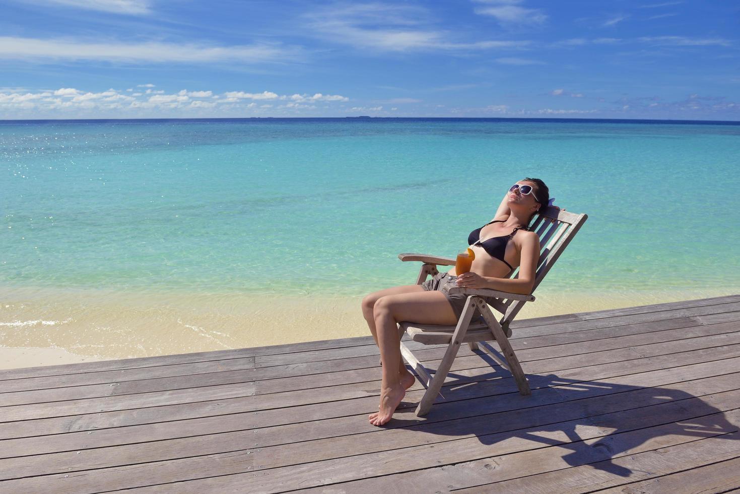 Beautiful young woman with a drink by the sea photo