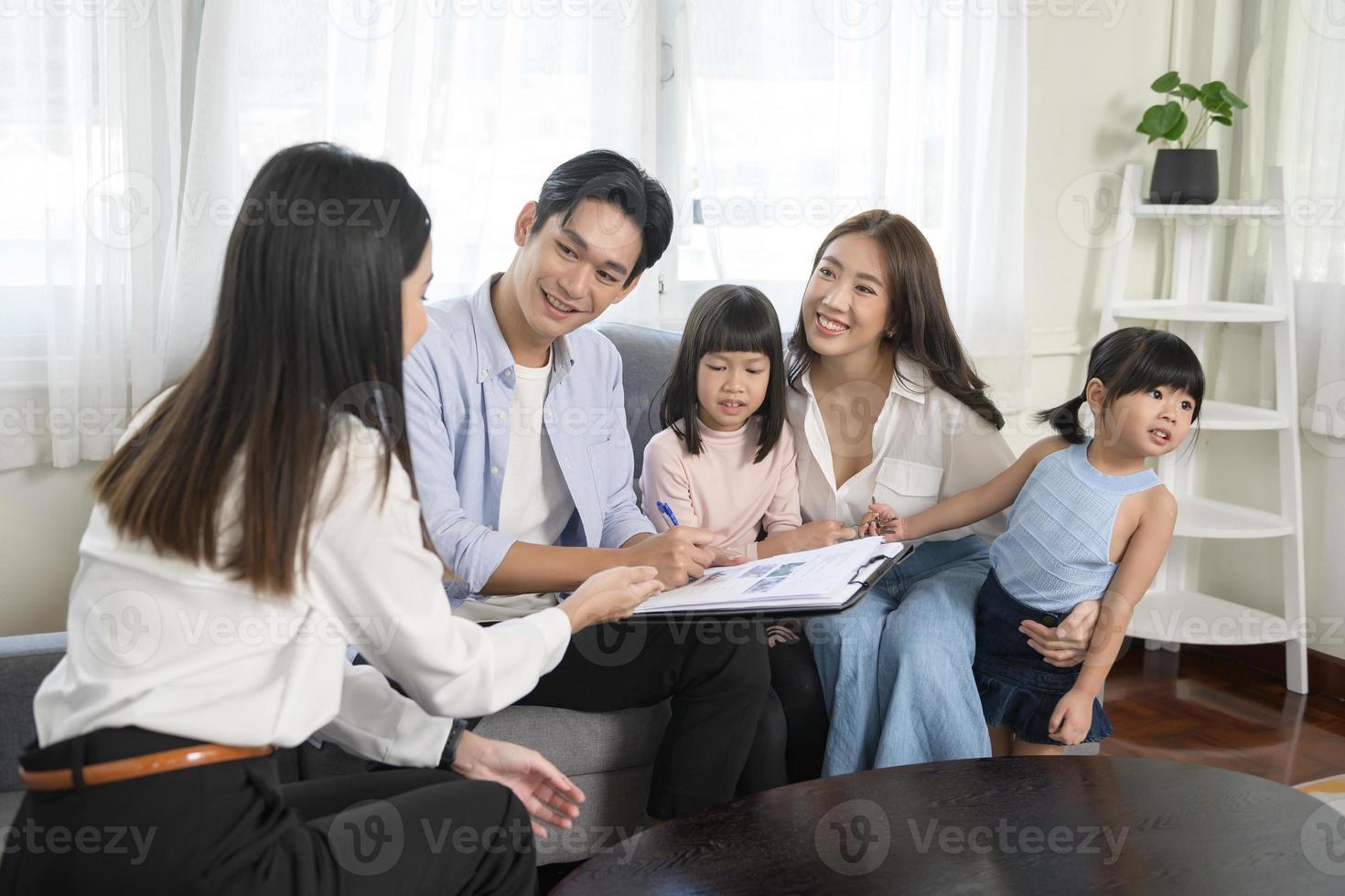 Asian family meeting with female real estate agent or insurance consultant offering promotions , Mortgage, loan, property and medical health insurance concept. photo