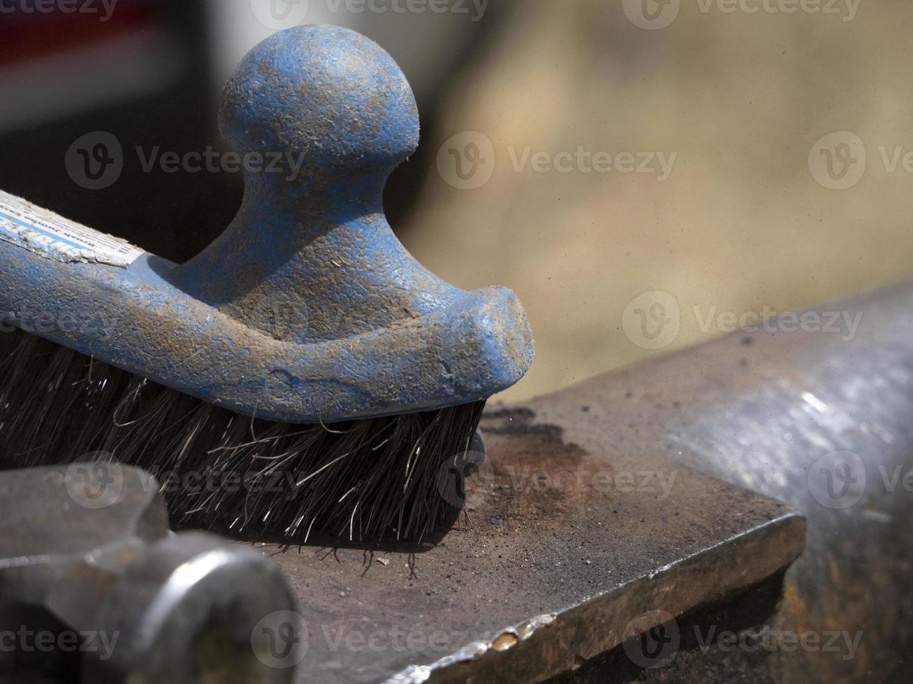 Blacksmith shoeing a donkey and cleaning hoof photo