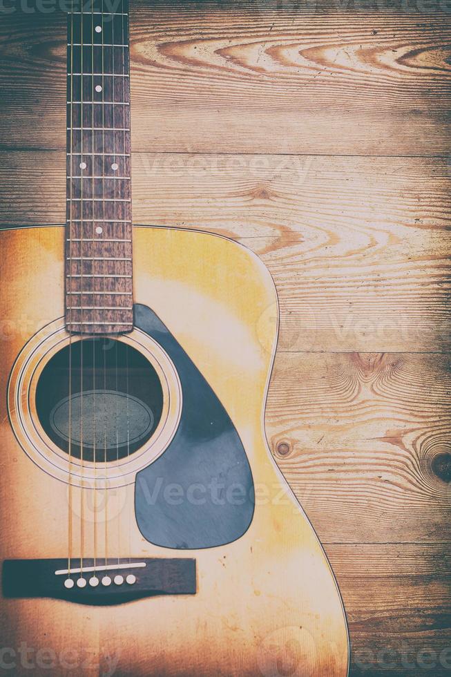 Vintage style photography of acoustic guitar on rough wooden background photo