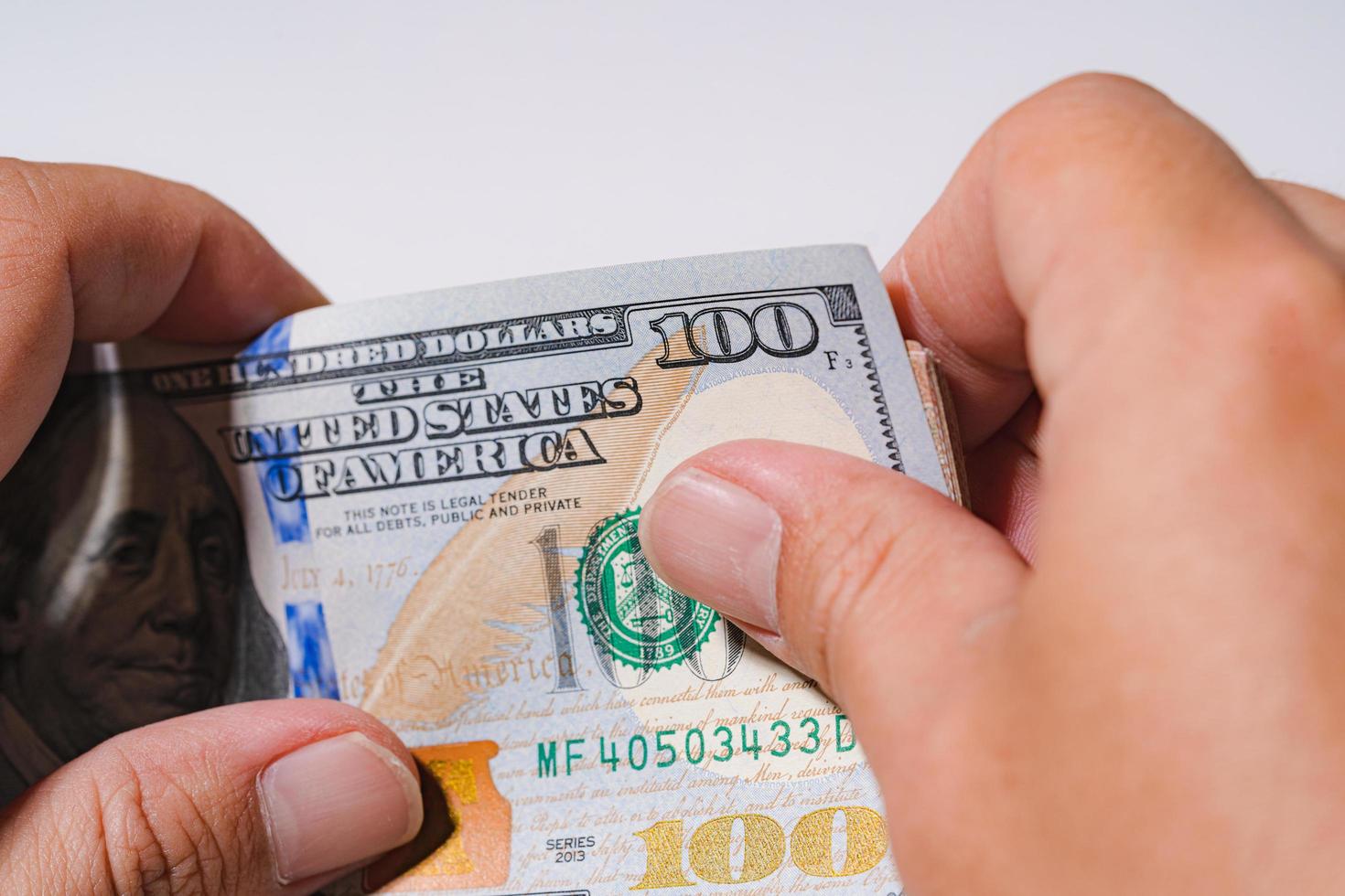 Business man count money a pile of hundred stack US dollar USD, Pay, exchange and looking at numbers 100 for business bills investment and close up macro photography isolated on white background. photo