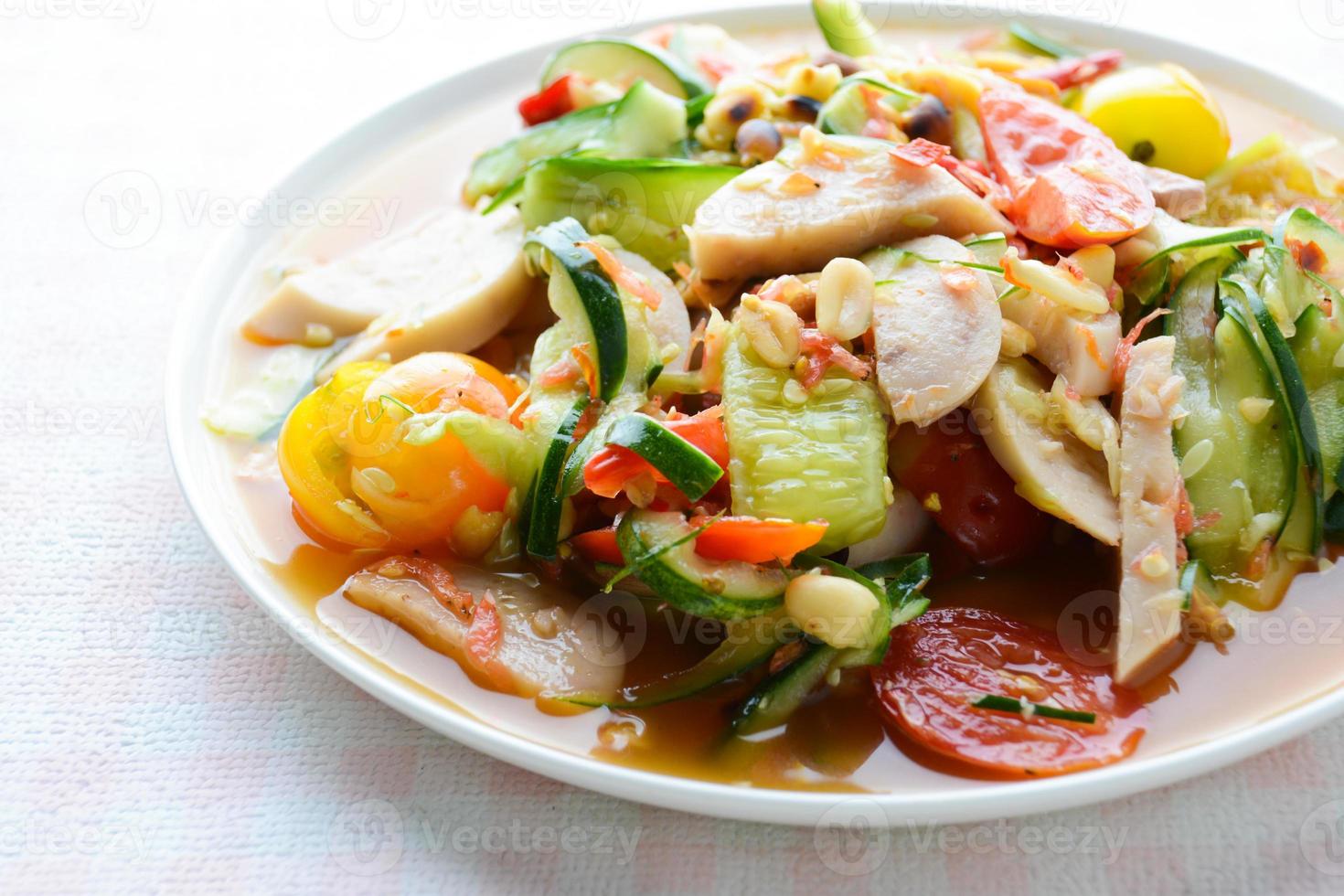Ensalada de pepino con salchichas de cerdo en conserva, comida popular tailandesa llamada som tum tang, verduras mixtas calientes y picantes. foto