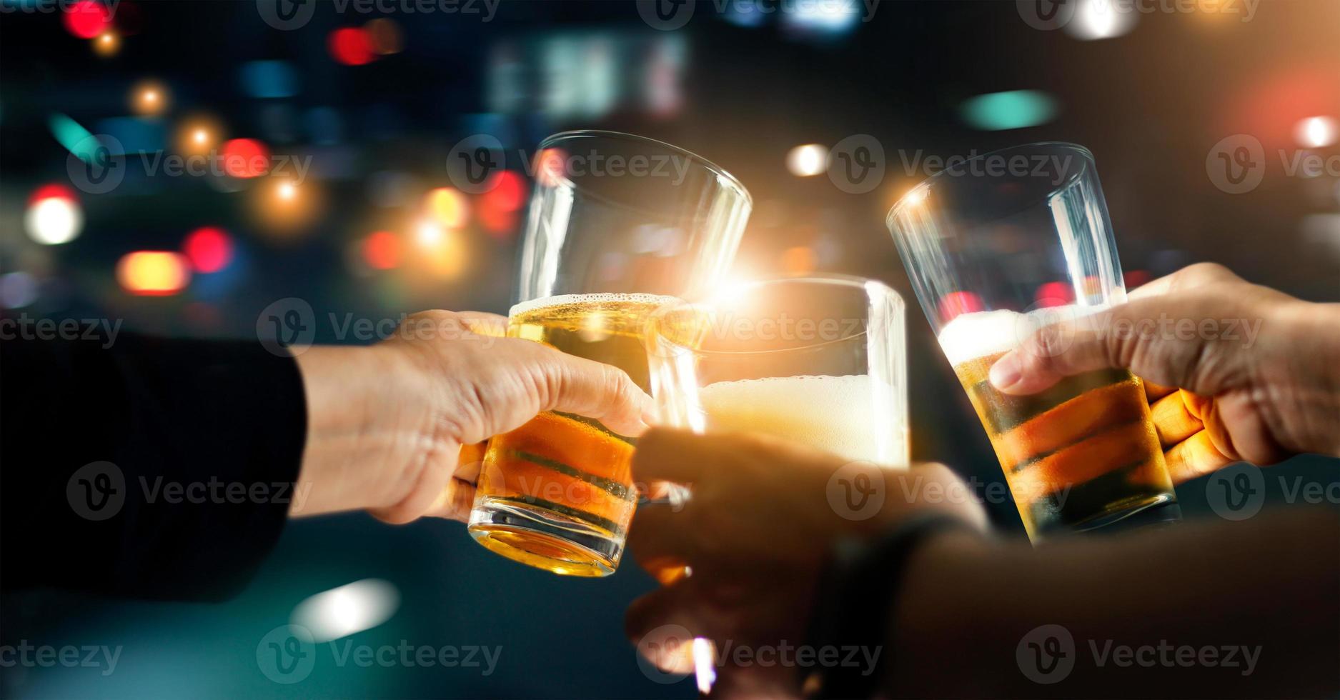 vítores tintineo de amigos con bebida de cerveza en la noche de fiesta después del trabajo en un colorido fondo borroso, grupo de jóvenes felices divirtiéndose junto con la amistad. foto