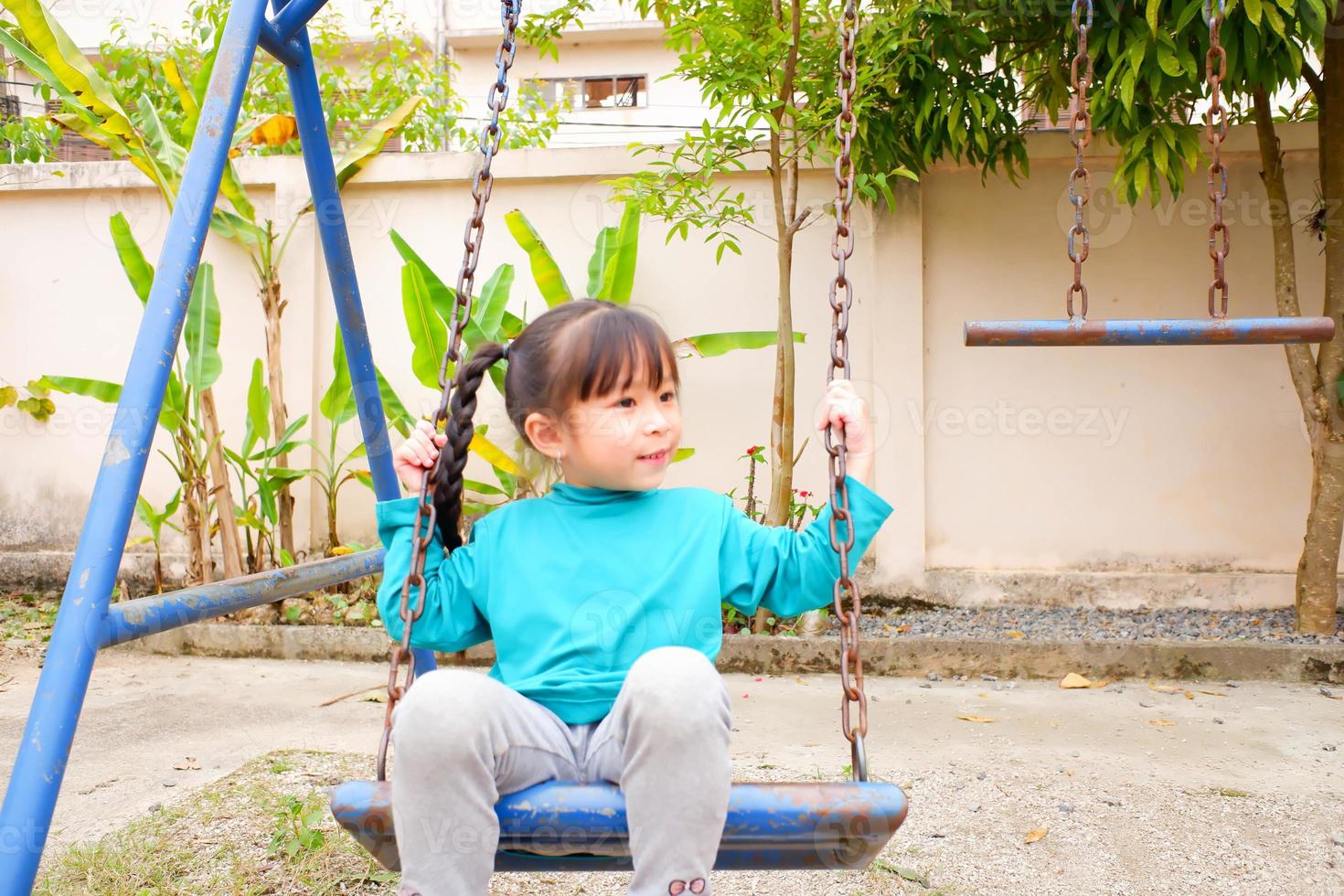 retrato de una niña que juega en el patio de recreo después de la escuela nuevo concepto normal. paseo otoñal de los estudiantes de jardín de infantes en el patio de la escuela. foto