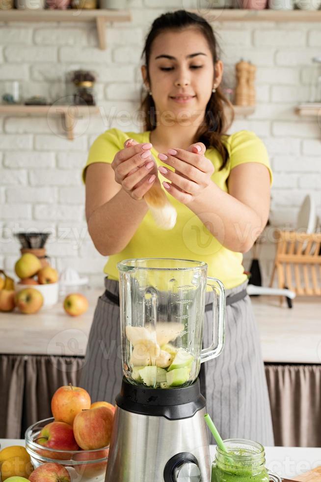 Young woman making banana smoothie at home kitchen photo