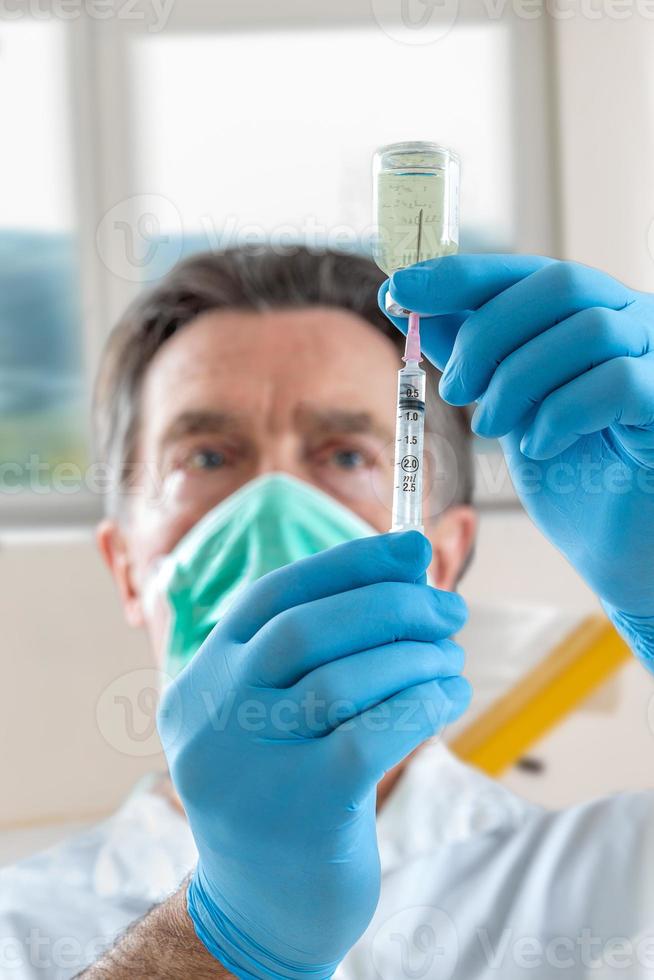 The doctor fills a syringe with vaccine on blurred background. photo