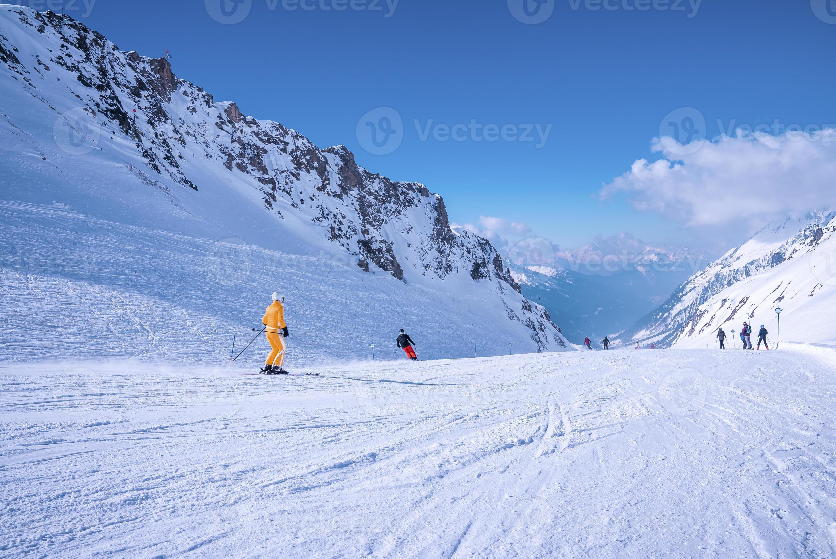 Skiers sliding down snowy slope on mountain at winter resort