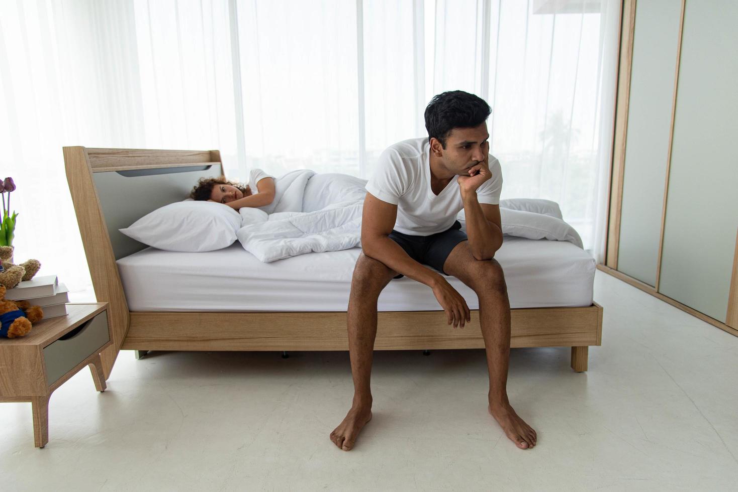 Couple have a family problem. Young upset man have conflict with girlfriend lying on bed. photo