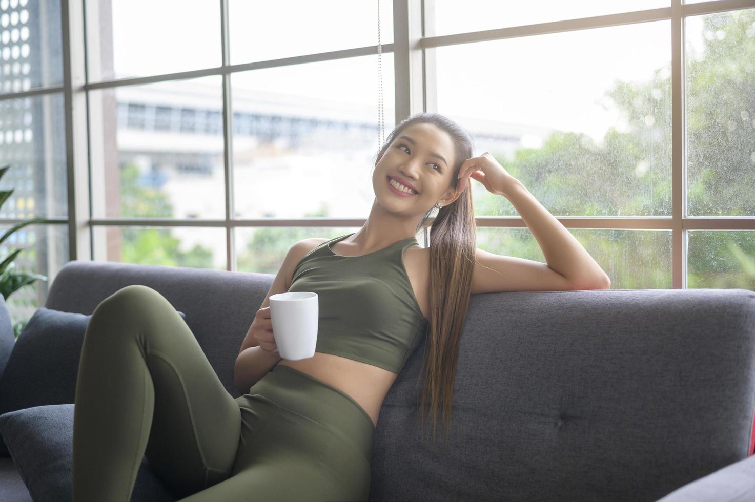 mujer joven fitness en ropa deportiva tomando una taza de café después de hacer ejercicio en casa, saludable y estilos de vida. foto