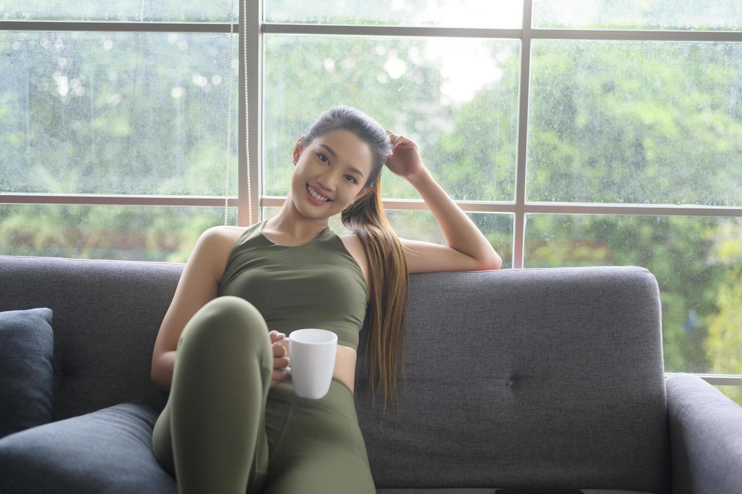 mujer joven fitness en ropa deportiva tomando una taza de café después de hacer ejercicio en casa, saludable y estilos de vida. foto