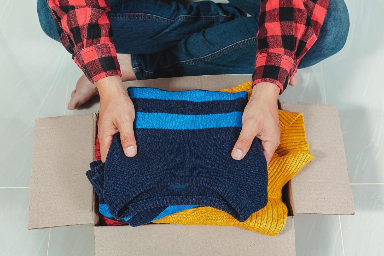 man holding a crate of second-hand clothes unused clothes photo