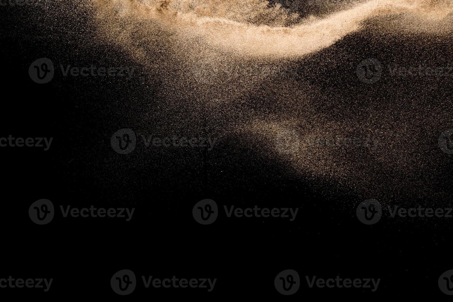 Dry river sand explosion. Golden colored sand splash agianst dark background. photo