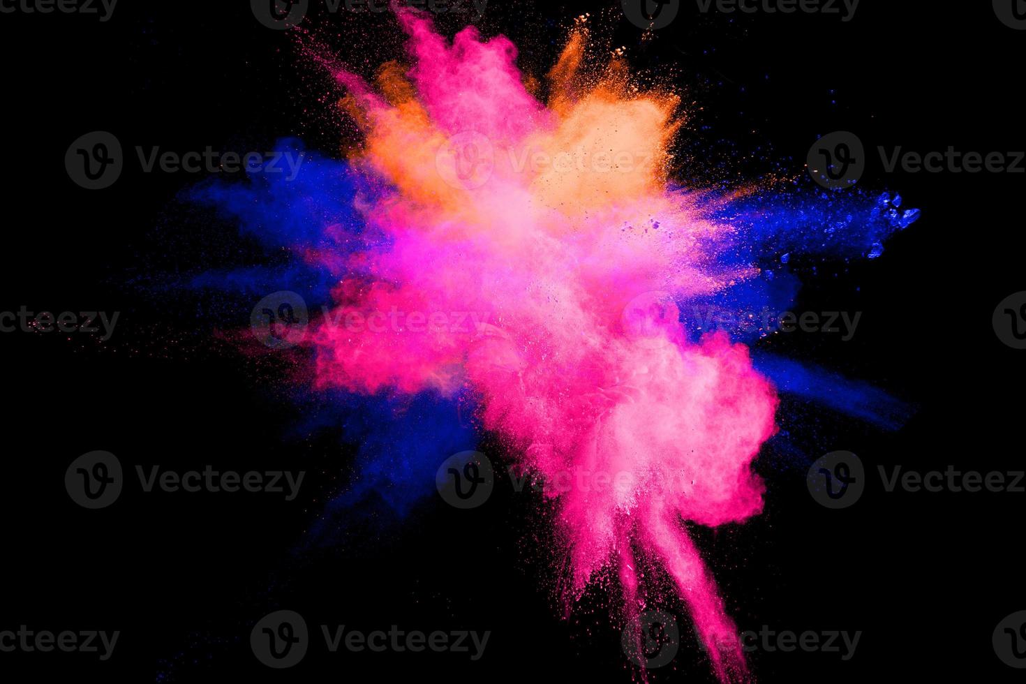 Abstract multicolored powder explosion on black background. Color dust particle splattered on background. photo